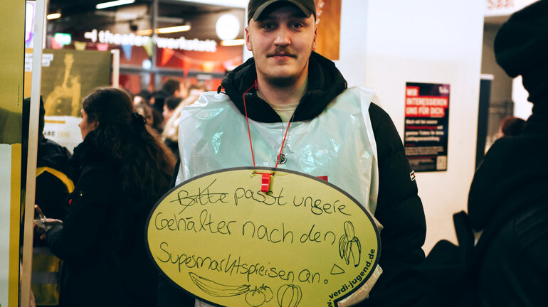Eine Person trägt am Jugendstreiktag der Tarifrunde öffentlicher Dienst Bund und Kommunen 2023 in Hannover ein Schild um den Hals auf dem steht: passt unsere Gehälter nach den Supermarktpreisen an