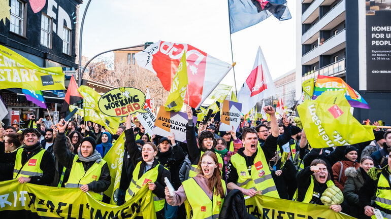 Große Gruppe Demonstrierender läuft lautstark mit gelben verdi Westen, diversen Fahnen, Schildern und Tarifrebellinnen Banner in Richtung Kamera. Anlass ist der verdi Jugendstreiktag der Tarifrunde öffentlicher Dienst Bund und Kommunen in Berlin 2023