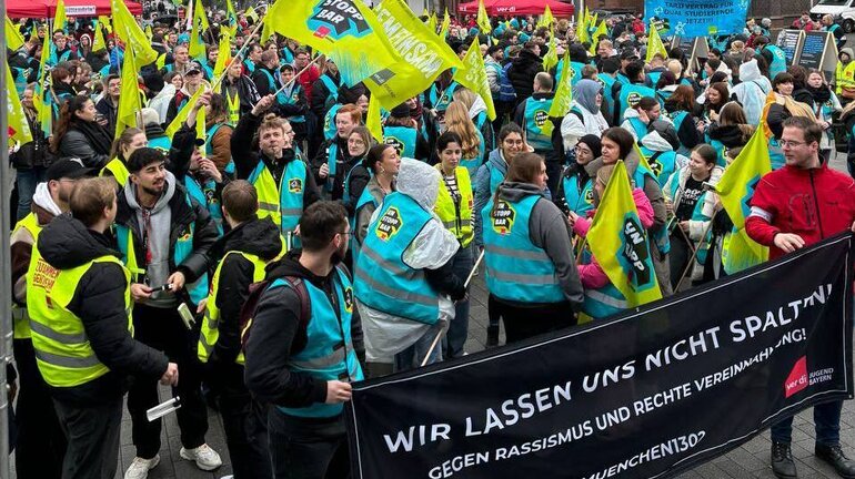 eine Gruppe an Personen streikt mit den Warnwesten und Fahnen der ver.di Jugend.