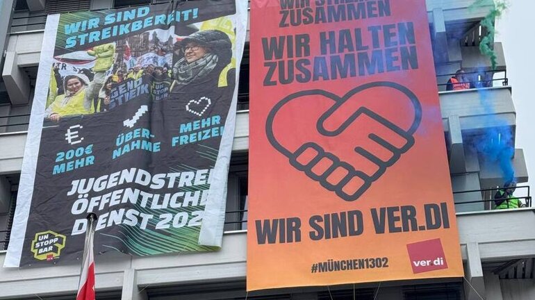 von einem Haus hängen zwei Banner mit den aktivierenden Nachrichten der ver.di Jugend.