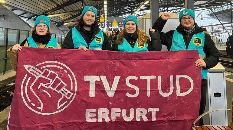 fünf junge Personen tragen Unstoppbar Streikwesten und Mützen und halten ein Banner, auf dem "TV Stud Erfurt" steht.